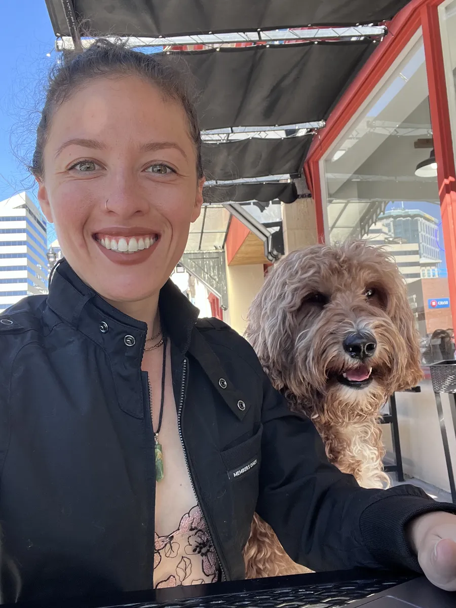 Destiny Cabrales smiling beside her dog outdoors